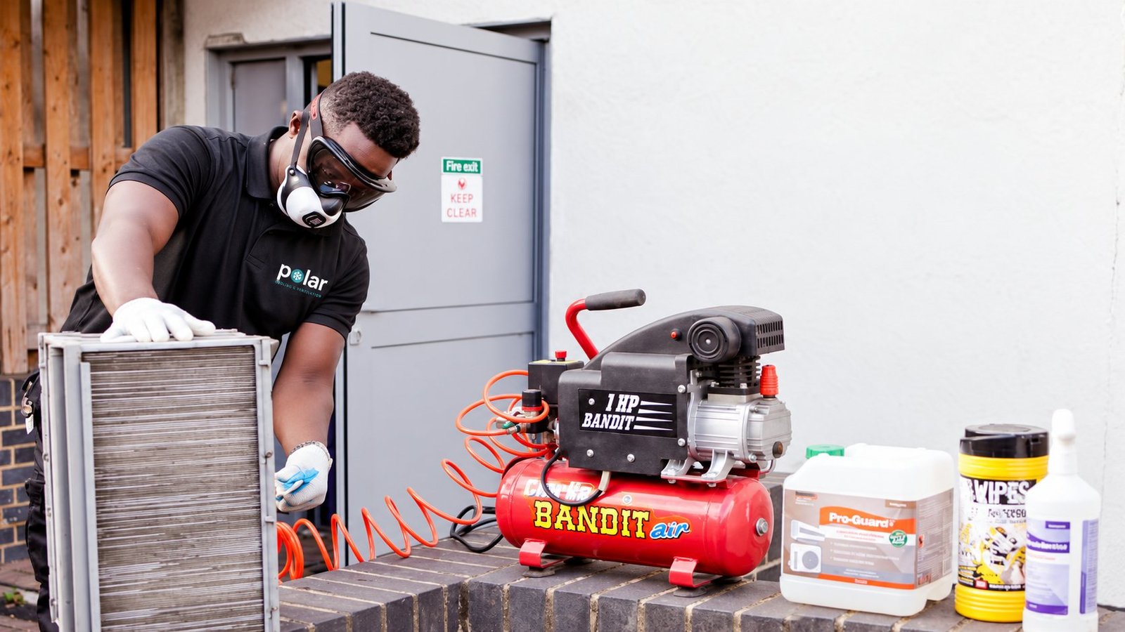 Polar engineer cleaning an air conditioning coil with compressed air