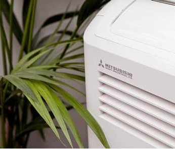 Portable Mitsubishi Heavy Industries air conditioning unit beside a house plant
